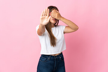 Young Uruguayan woman isolated on pink background making stop gesture and covering face