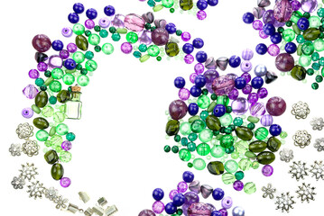 A layout of green and violet beads, sewing threads and other jewellery suppliers isolated on a white background.