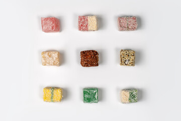 Many pieces of Turkish Delight set on three rows, empty white background. Colorful sweet cubes of lokum. Eastern traditional dessert. Copy space.