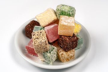 Many pieces of Turkish Delight set on a pile on little white plate. Empty background. Colorful sweet cubes of lokum. Eastern traditional dessert. Copy space.