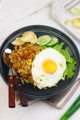 Nasi Goreng or Fried Rice, one of Indonesian popular food, topping with sunny side up egg, cucumber slices, lettuce and crackers. Top view, copy space for text.