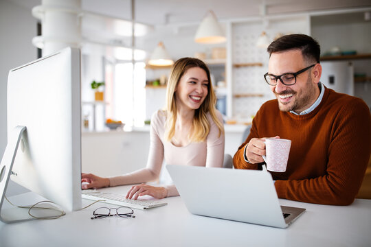Positive couple having fun while working together remotely at home using modern technology
