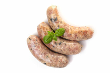 Raw or cooked homemade breakfast sausages decorated with basil leaves, isolated on a white background