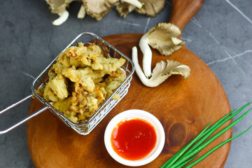 Jamur krispi or crispy fried mushroom served with chili sauce. Marble black background.