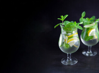 Mojito on a black background banner. Summer soft drinks with copy space. Lemon, lime, mint, ice,...