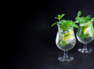 Mojito on a black background banner. Summer soft drinks with copy space. Lemon, lime, mint, ice, water. Bar menu, two misted glasses with room for text. Summer drink.