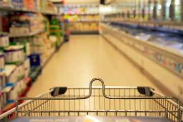 Abstract, market cart in a supermarket aisle with unfocused color filled interior shelves