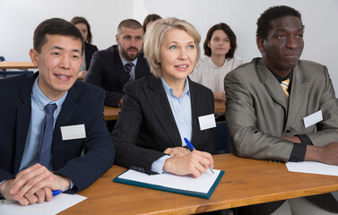 Fototapeta premium International group of business people listening to presentation at tables in boardroom