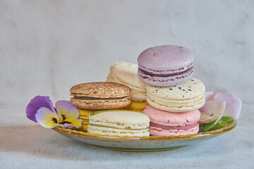 Colorful delicious macaroons on a green ceramic saucer .