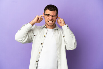Brazilian man over isolated purple background frustrated and covering ears