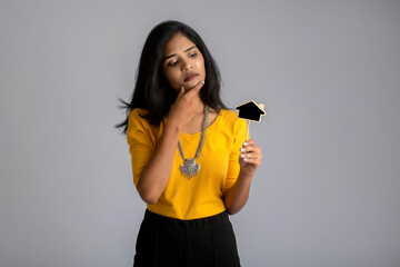 A young girl or businesswoman holding a little cutout board and posing on a gray background.