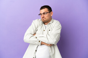 Brazilian man over isolated purple background making doubts gesture while lifting the shoulders