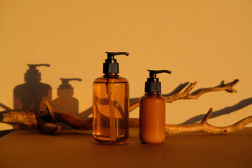 SPA natural organic cosmetics for personal hygiene. Amber glass pump bottles and wooden branch.