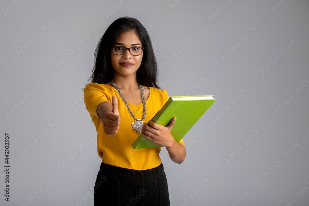 Poster pretty young girl posing with the book on grey background