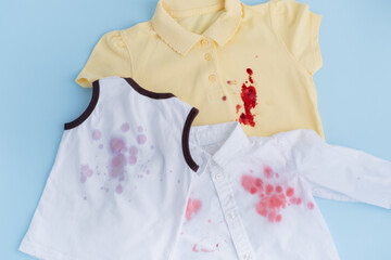 Dirty stains of juice and blood on children's clothes. Laundry collection.isolated on blue background, top view. dirt stains for cleaning and washing concept