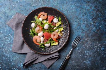 Healthy salad with fresh arugula, mozzarella cheese, tasty shrimps, grapefruit and avocado
