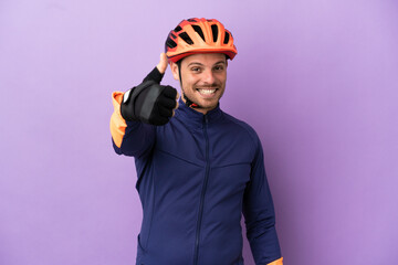 Young Brazilian cyclist man isolated on purple background with thumbs up because something good has happened