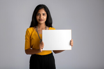 A young girl or businesswoman holding a signboard in her hands on a gray background.