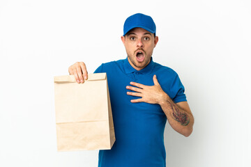 Brazilian taking a bag of takeaway food isolated on white background surprised and shocked while looking right