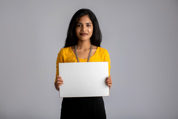 A young girl or businesswoman holding a signboard in her hands on a gray background.
