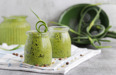 Homemade organic pesto sauce made from fresh arrows of garlic,dill and oil in a glass jar.