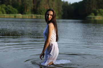 Beautiful brunette woman in white dress in the lake