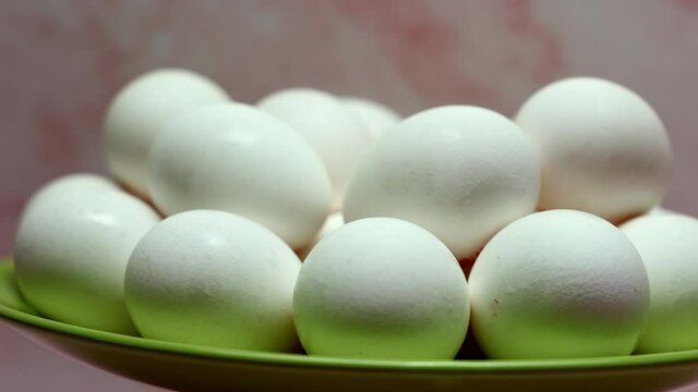 Rotating White Chicken Eggs In A Green Plate On A Pink Background.