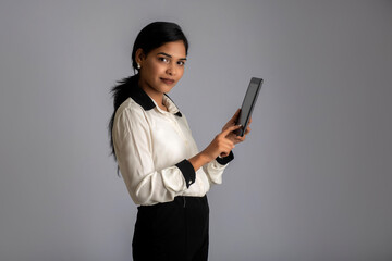 Young Indian girl using a mobile phone or smartphone on gray background