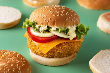Crispy chicken burger with cheese on green background	