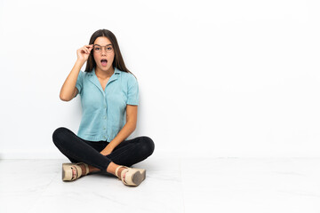 Fototapeta na wymiar Teenager girl sitting on the floor with glasses and surprised
