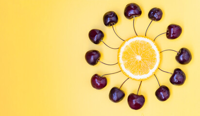 Cherries and an orange in the shape of a clock. The berries are spread out on the dial. Summer Flat lay. Copy space.