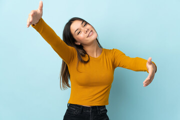 Teenager girl isolated on blue background presenting and inviting to come with hand