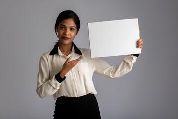 A young woman or businesswoman holding a signboard in her hands on a gray background.