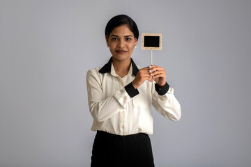 young woman or business woman holding a little cutout board in her hands on a gray background.