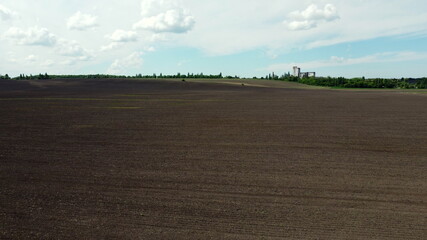 Obraz premium Aerial drone view flight over huge plowed field and blue sky.