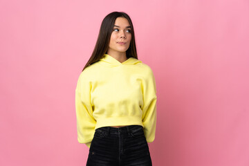 Teenager girl isolated on pink background making doubts gesture looking side