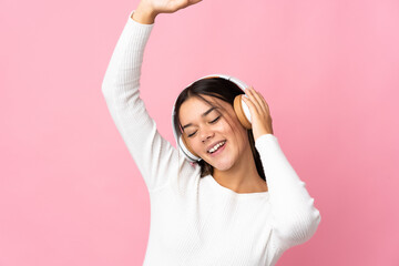 Teenager girl isolated on blue background listening music and dancing