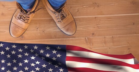 Composition of feet in work boots and american flag, on wooden floor