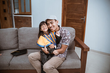 Kindergarten graduation. asian father embrace his daughter at home after graduation ceremony at home