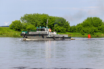 A small ship sails along the Neman River. River navigation