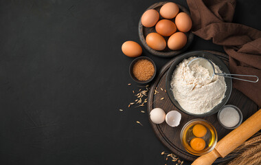Ingredients for cooking flour dishes. Flour, eggs, sugar on a black background.