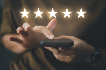 close up Woman hand using smart phone and give five star symbol to increase rating of company...