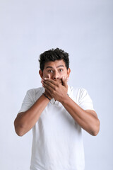 Young indian man shocked and covering mouth with hand.