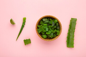 Green fresh aloe vera leaf in wooden bowl on pink background. Natural herbal medical plant, skin...