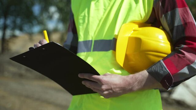 Builder with hard hat inspects construction site. Close-up.