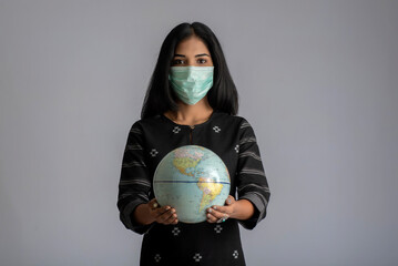 Young girl holding world globe with a medicine face mask. World epidemic of coronavirus or new normal concept.