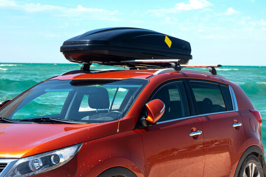 Travel to the sea by car. Crossover with roof rack stands against the background of the sea.