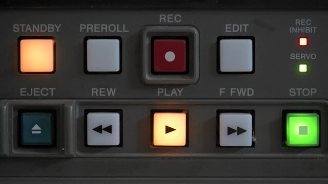 Close up of the control panel of an old broadcasting recorder where we can see the play buttons while a person presses the stop button
