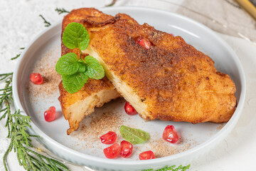 Traditional Christmas Rabanadas with lemon zest, pomegranate, pine nuts and cinnamon. Spanish Torrijas or french toasts close up on the countertop
