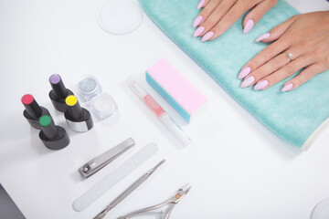 Cropped shot of manicure equipment and female hands on white table at nail salin